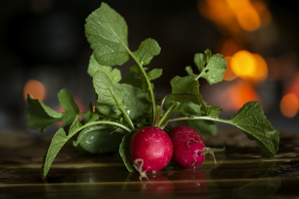 Close-up of fresh radishes with leaves on a wooden table, highlighting freshness.